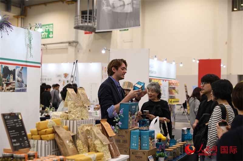 當(dāng)?shù)貢r(shí)間10月5日，在第21屆釜山國(guó)際美食博覽會(huì)上，意大利展商向參觀者們介紹的意大利食品。人民網(wǎng)記者 莽九晨攝
