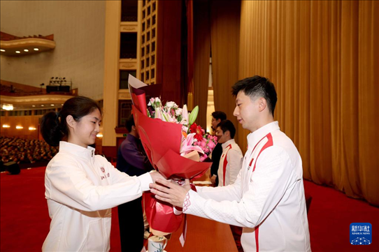 11月15日，一名學(xué)生代表在報(bào)告會(huì)上向乒乓球運(yùn)動(dòng)員馬龍（右）獻(xiàn)花。新華社記者 李明 攝