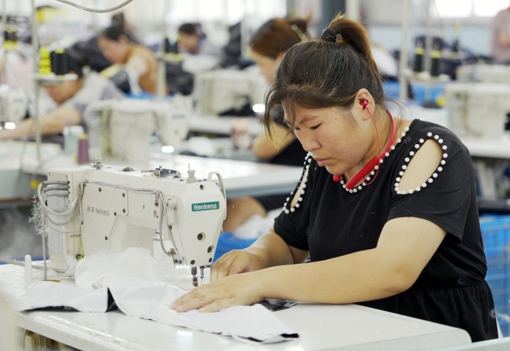 5月20日，村民在李寨村服裝加工廠內(nèi)忙碌。河南省周口市沈丘縣馮營鎮(zhèn)李寨村地處豫東平原。近年來，乘著脫貧攻堅與鄉(xiāng)村振興政策的東風(fēng)，李寨村積極探索產(chǎn)業(yè)發(fā)展模式，通過“龍頭企業(yè)+村集體經(jīng)濟+農(nóng)戶”的方式，逐漸發(fā)展形成肉牛養(yǎng)殖、設(shè)施農(nóng)業(yè)、服裝加工、康養(yǎng)民宿等產(chǎn)業(yè)，以產(chǎn)業(yè)振興助力鄉(xiāng)村振興。新華社記者 李嘉南 攝
