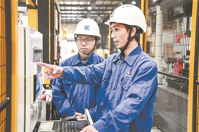 在廣西柳工機(jī)械股份有限公司生產(chǎn)車間內(nèi)，一名高級(jí)技師（右）給徒弟講解數(shù)控設(shè)備操作細(xì)節(jié)。新華社記者 曹祎銘攝
