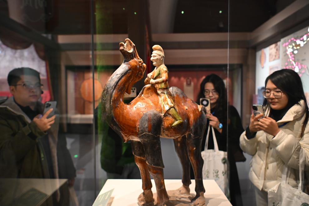 1月15日，觀眾在拍攝“長安三萬里——陜西唐代文物精華展”展出的三彩胡人騎駝俑。（新華社記者 孫凡越 攝）