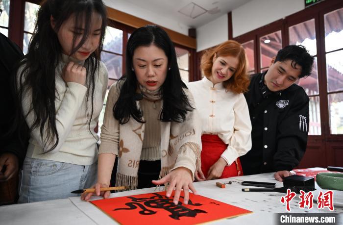1月20日，西泠印社社員李硯（左二）為外籍留學(xué)生講述蛇年福字貼創(chuàng)作靈感。當日，來自巴西、馬來西亞、加納、哈薩克斯坦的外籍留學(xué)生在浙江杭州西泠印社體驗福貼、春聯(lián)和篆刻，感受古老的中國傳統(tǒng)文化。中新社記者 王剛 攝