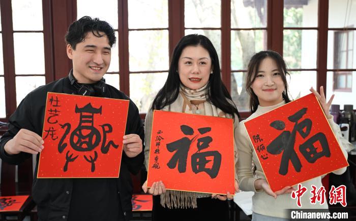 1月20日，外籍留學(xué)生和西泠印社社員李硯(中)展示各自創(chuàng)作的福貼。當日，來自巴西、馬來西亞、加納、哈薩克斯坦的外籍留學(xué)生在浙江杭州西泠印社體驗福貼、春聯(lián)和篆刻，感受古老的中國傳統(tǒng)文化。中新社記者 王剛 攝