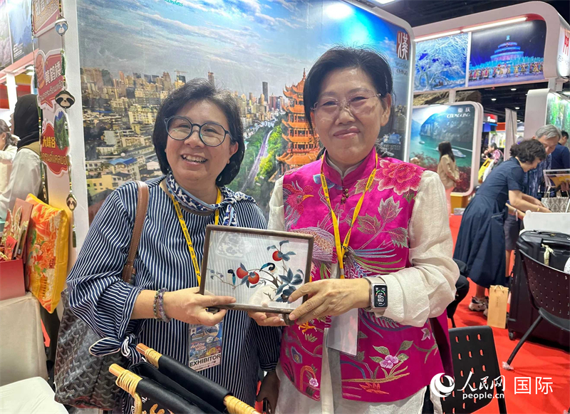 中國“大冶刺繡”傳承人劉小紅（右）參加泰國國際旅游展，向觀眾介紹中國非遺刺繡針法。人民網(wǎng)記者 簡承淵攝