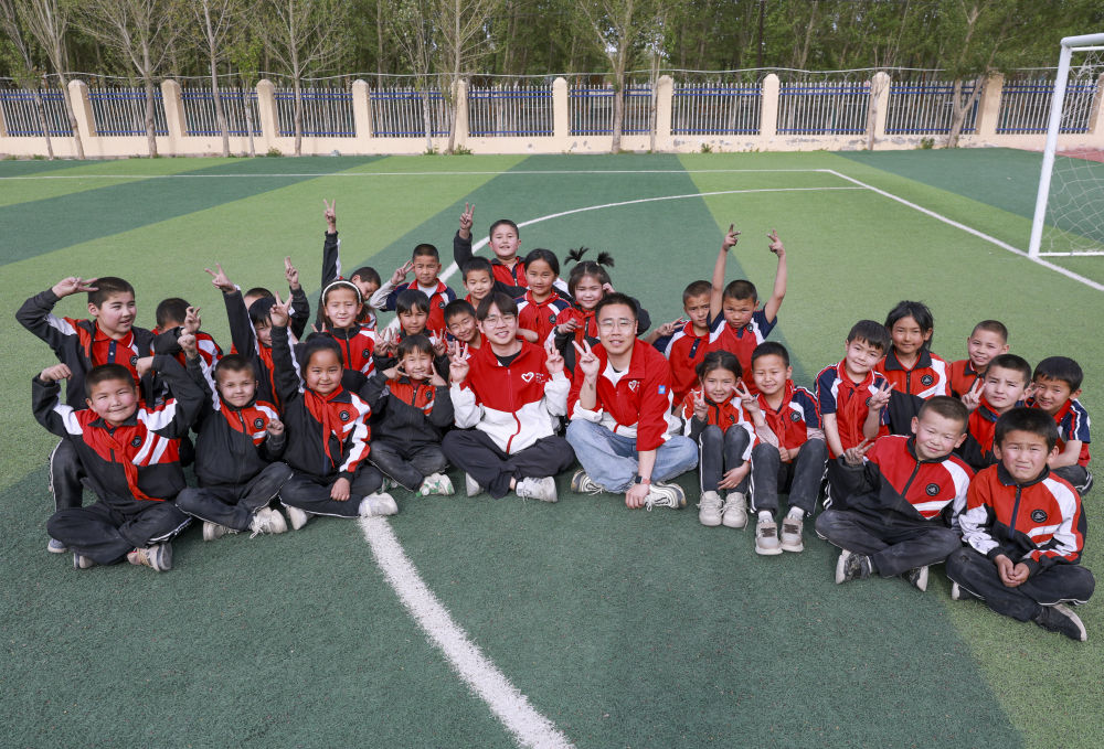 4月23日，在新疆克州阿圖什市哈拉峻鄉(xiāng)謝依特小學，支教教師王俊文（中左）、李軻凡（中右）和學生在一起。